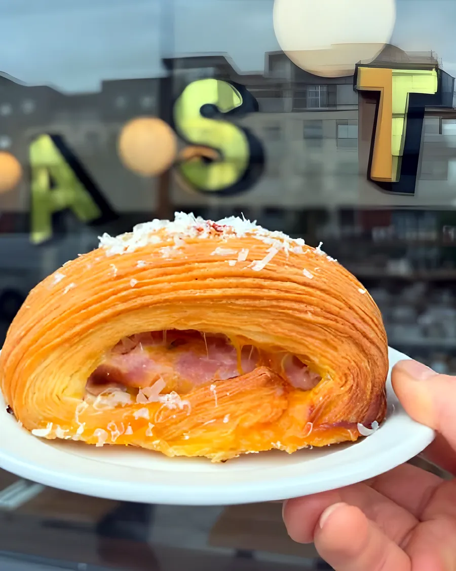 A ham and cheese croissant held up at the café window